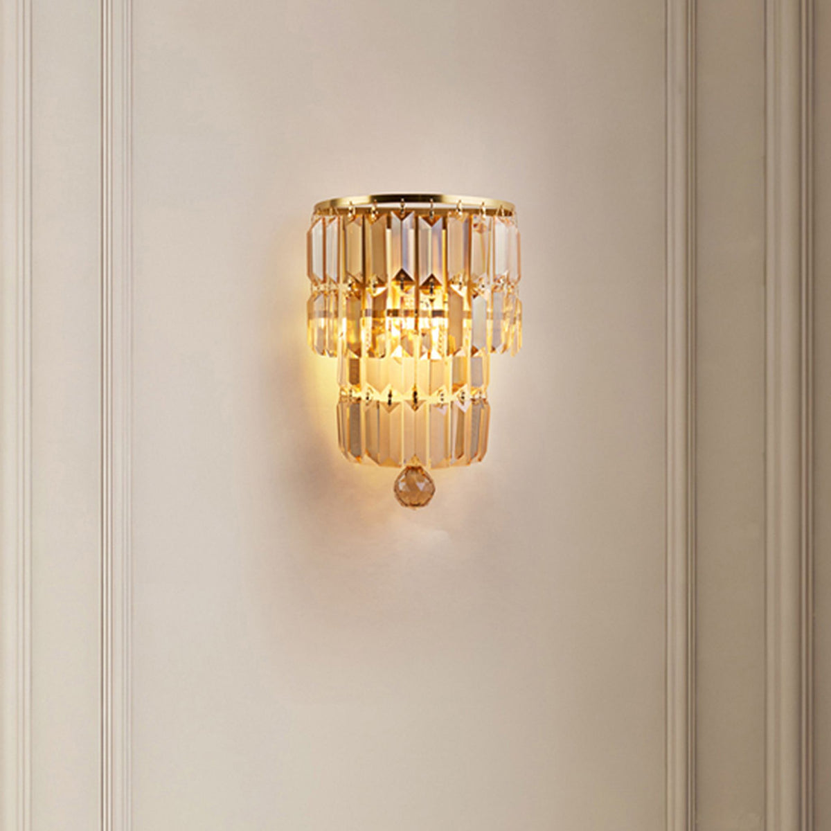 Empire champagne crystal wall light glowing on a cream panelled wall in an elegant hallway