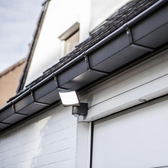 Lutec Sunshine Outdoor LED Black PIR Wall Light 7625701345 above a garage