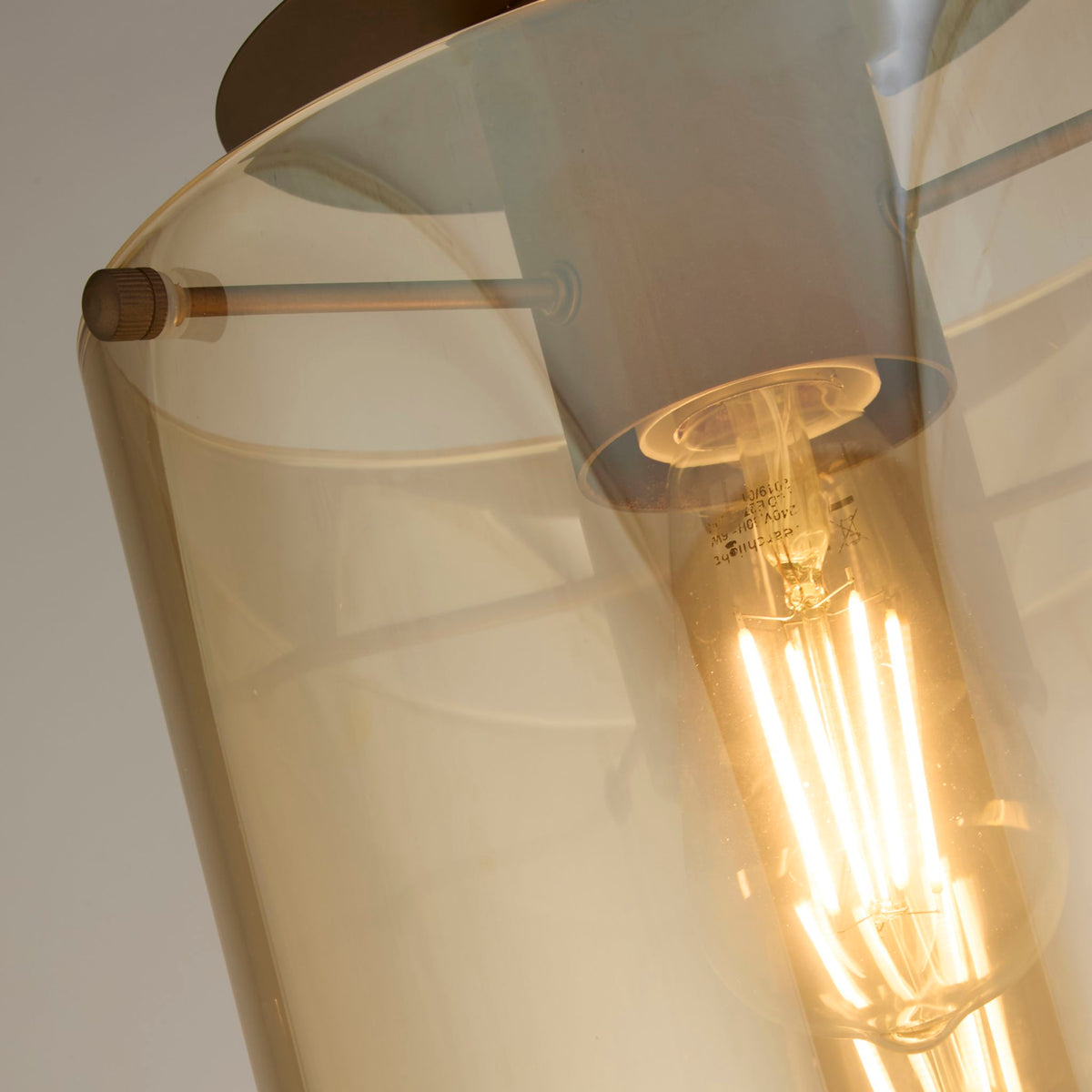 Close-up of the Sweden ceiling light's amber glass cylinder and glowing filament bulb