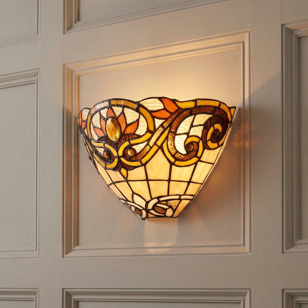 Illuminated Aintree Tiffany wall light with amber stained glass floral patterns on a cream paneled wall.