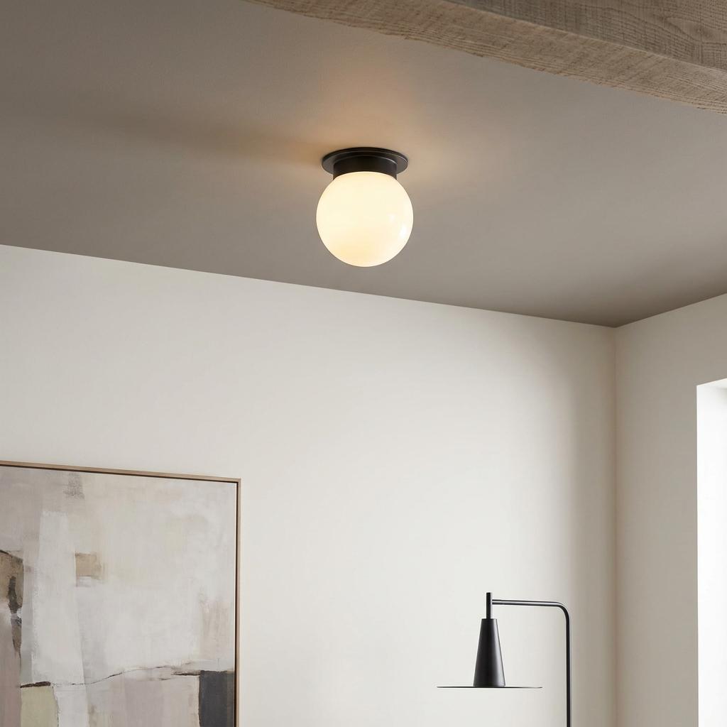 A glowing white opal glass globe ceiling light with a black base, flush-mounted in a minimalist room.