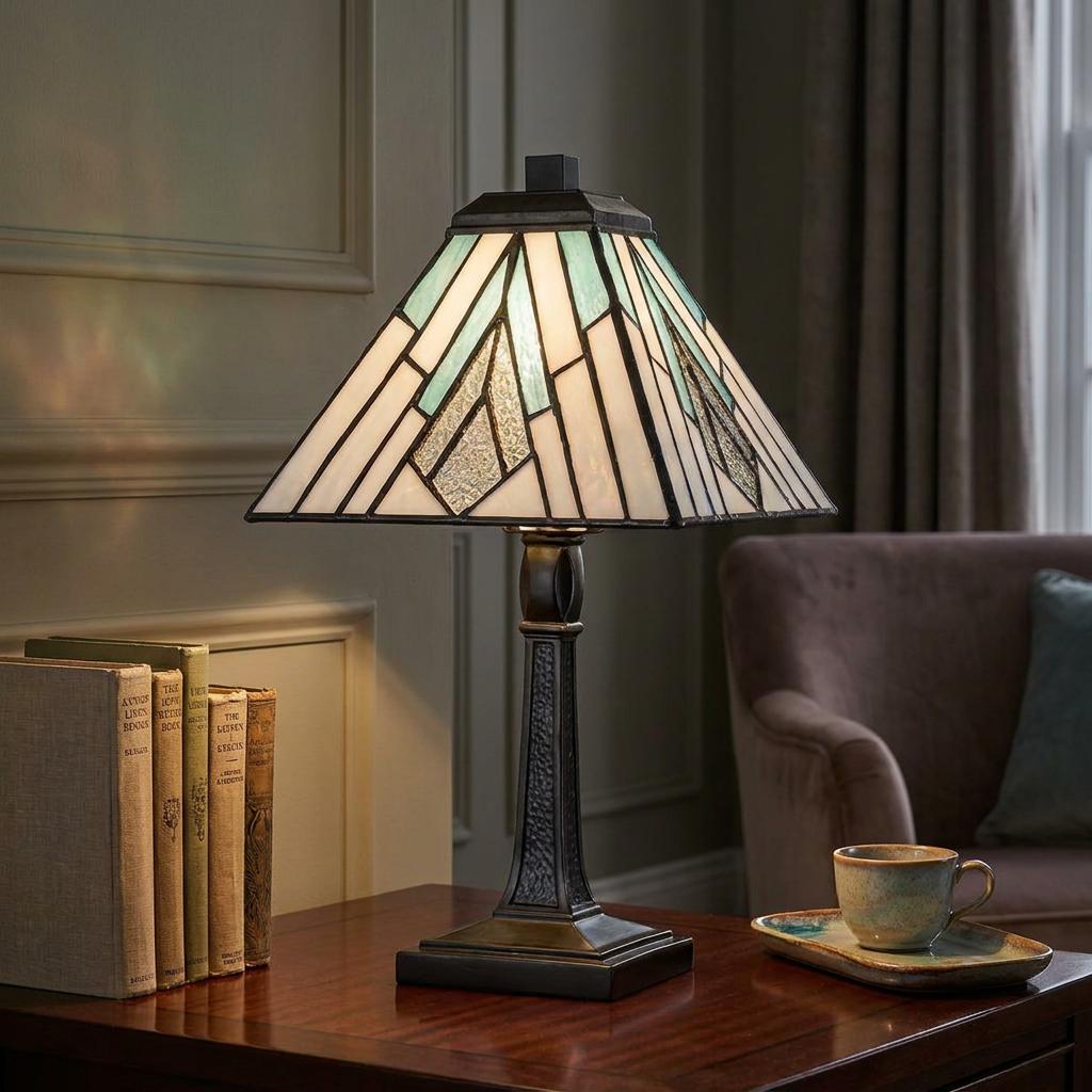 Geometric green and white Tiffany table lamp on a wooden table with books in a cozy living room.