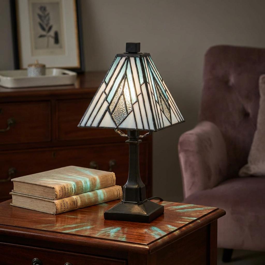 Art Deco Tiffany table lamp with a geometric glass shade, on a wooden side table casting patterned light.