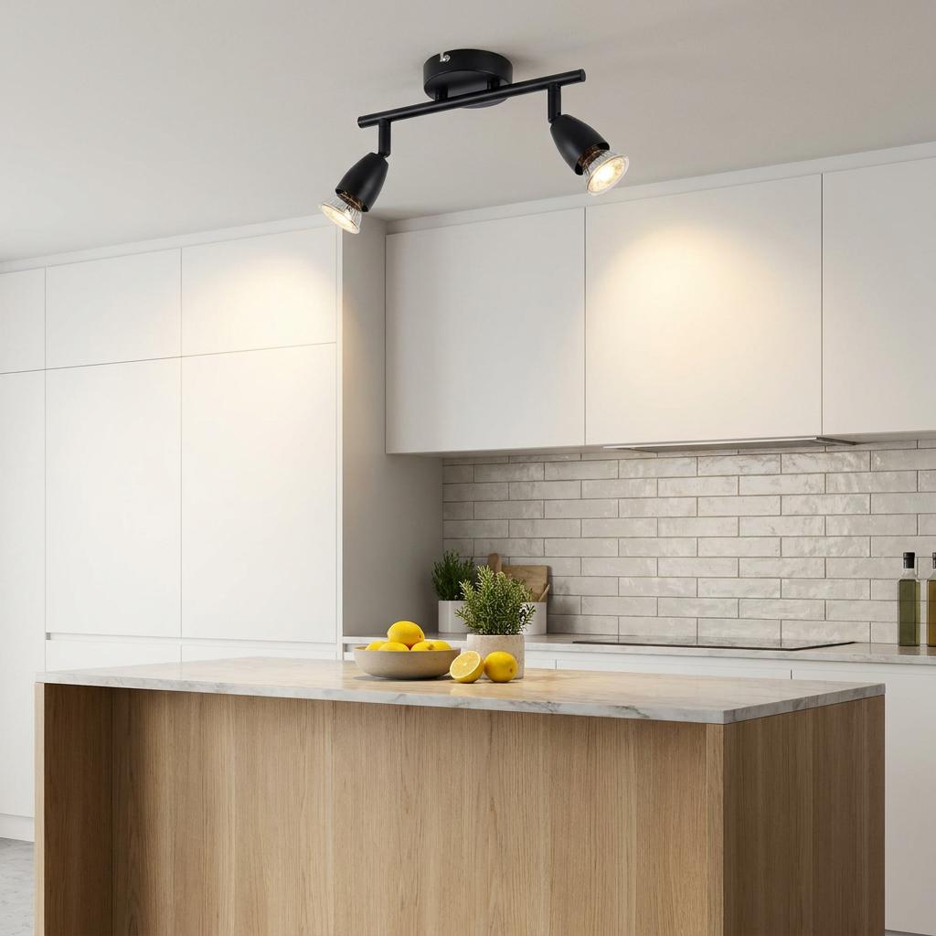 Amalfi 2-light black adjustable spotlight bar mounted on a kitchen ceiling illuminating white cabinets and an island.