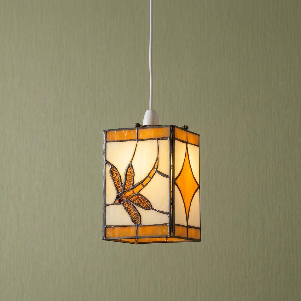 Rectangular Tiffany-style dragonfly pendant light shade with amber glass hanging against a green textured wall.