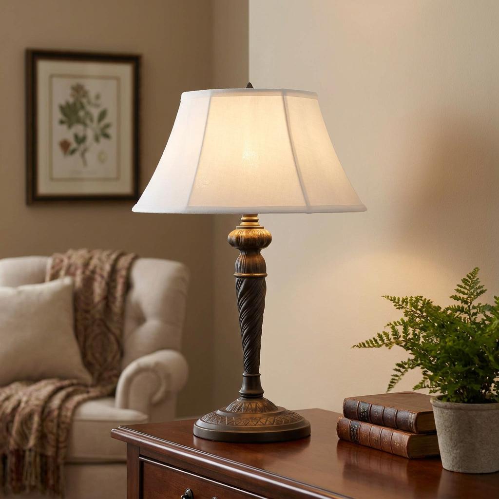 Antique bronze and black table lamp with a white linen shade on a wooden desk in a cozy room.