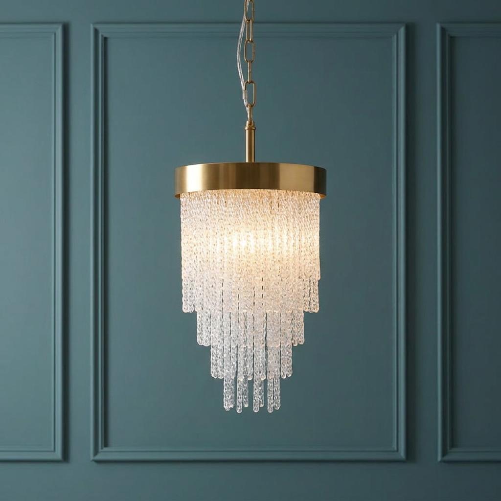 Elegant brass pendant light featuring a tiered cascade of textured glass rods against a teal paneled wall.