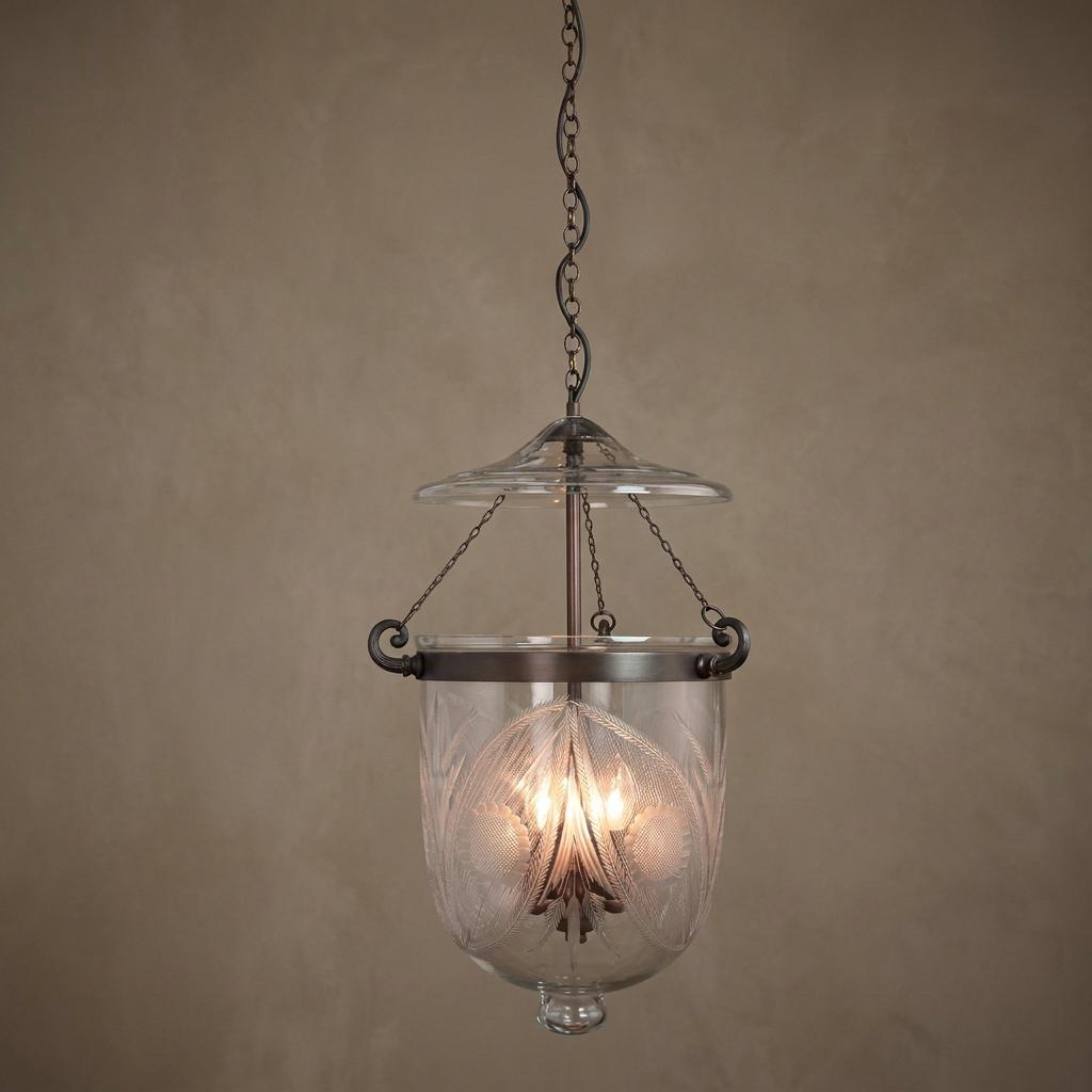 Antique bronze Georgian ceiling lantern with three lights and etched glass hanging from a chain against a neutral wall.