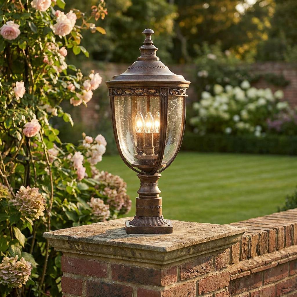 Antique bronze outdoor pedestal lantern with seeded glass and glowing bulbs, mounted on a brick pillar in a garden.