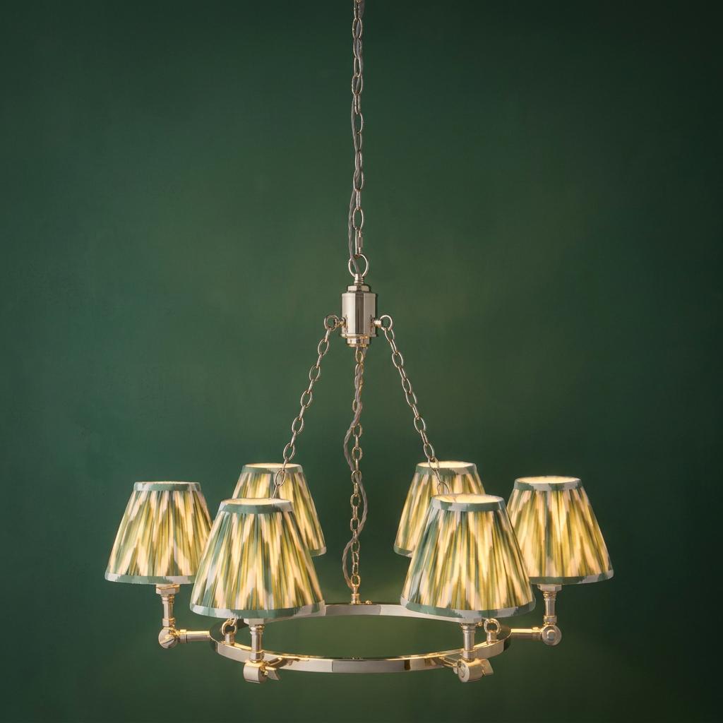 Arabella nickel chandelier with six green zigzag patterned lampshades against a dark green wall.