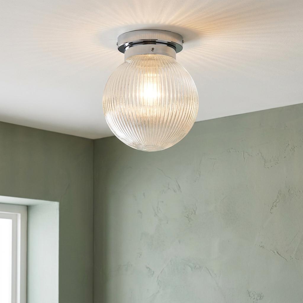 Art Deco prismatic glass globe flush ceiling light with a chrome base, casting a radial glow on a white ceiling.