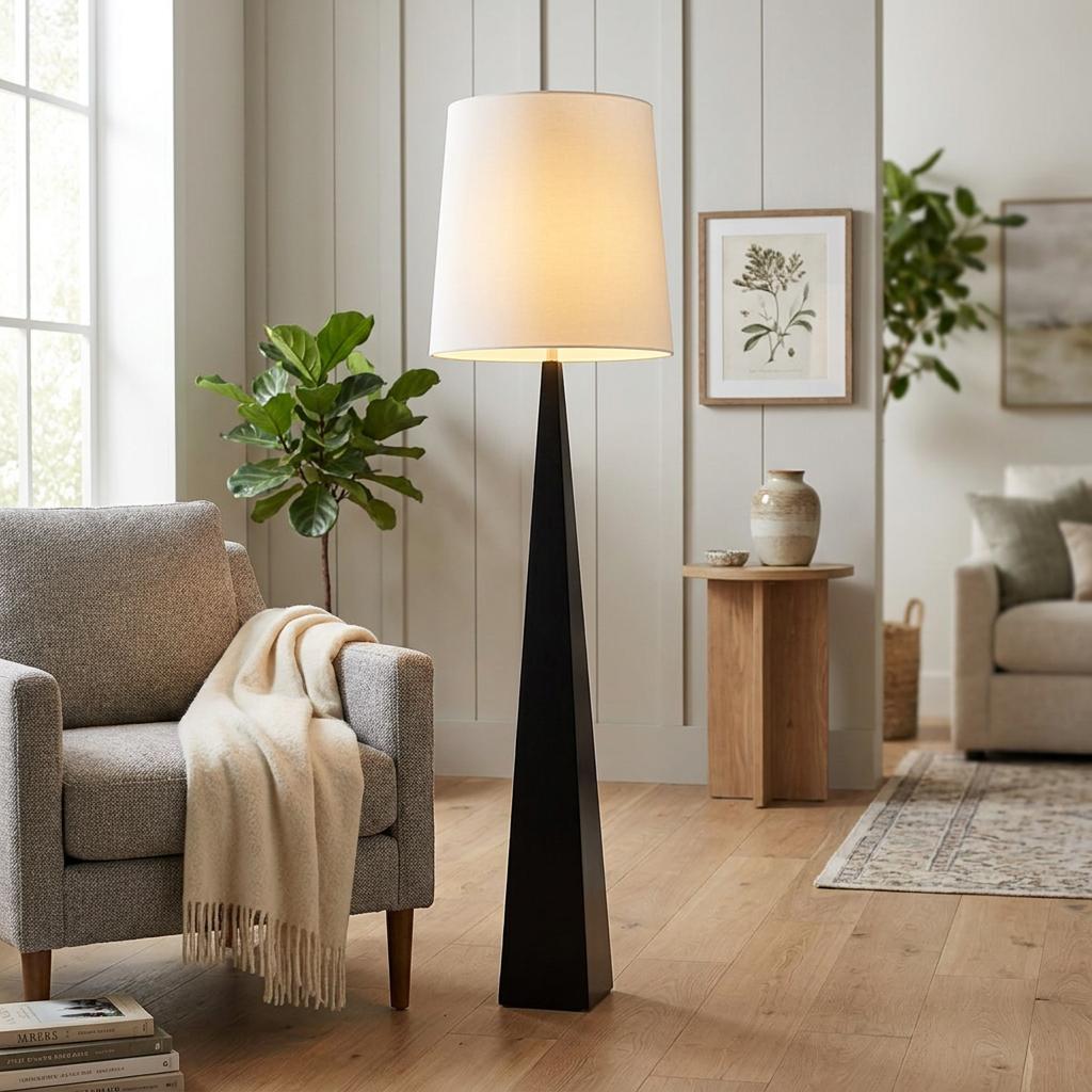 Modern floor lamp with a black tapered base and white drum shade in a bright, cozy living room.