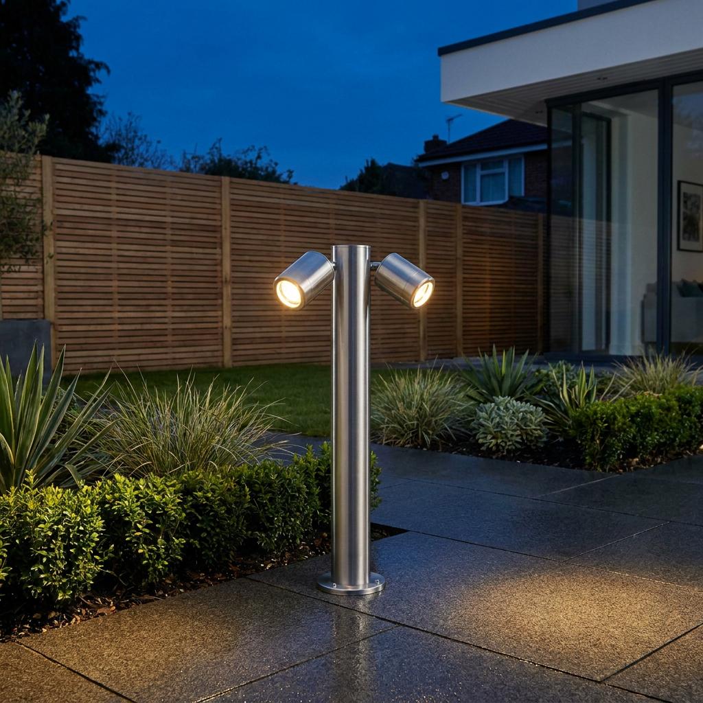 Silver twin adjustable bollard light illuminating a modern garden patio at night.