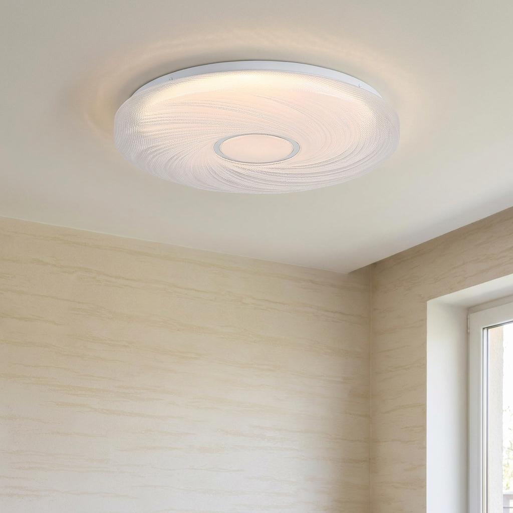 Aura flush ceiling light with white swirled textured diffuser, mounted on a plain ceiling in a beige room.