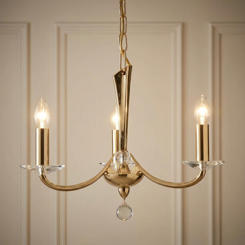 Bahia gold-plated cast brass 3-light chandelier with crystal accents against a neutral paneled wall.