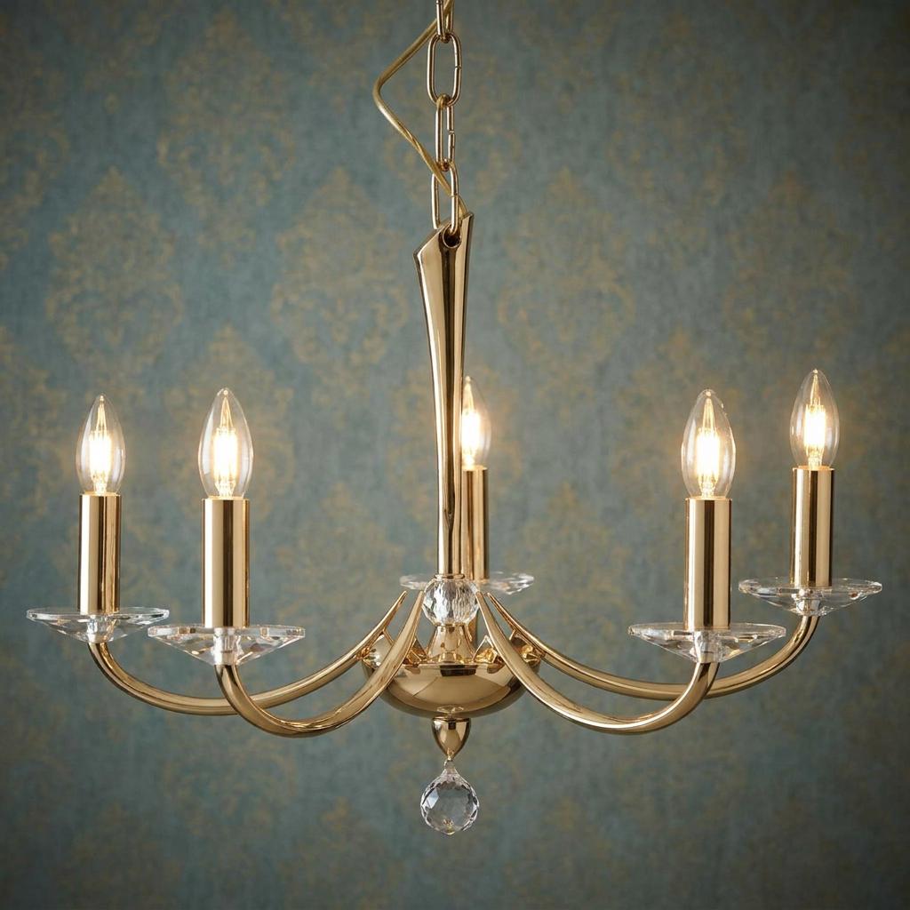 Gold-plated five-light cast brass chandelier with crystal bobeches against blue damask wallpaper.