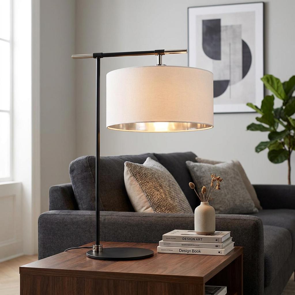 Modern black and nickel table lamp with a cream drum shade on a wooden side table in a contemporary living room.