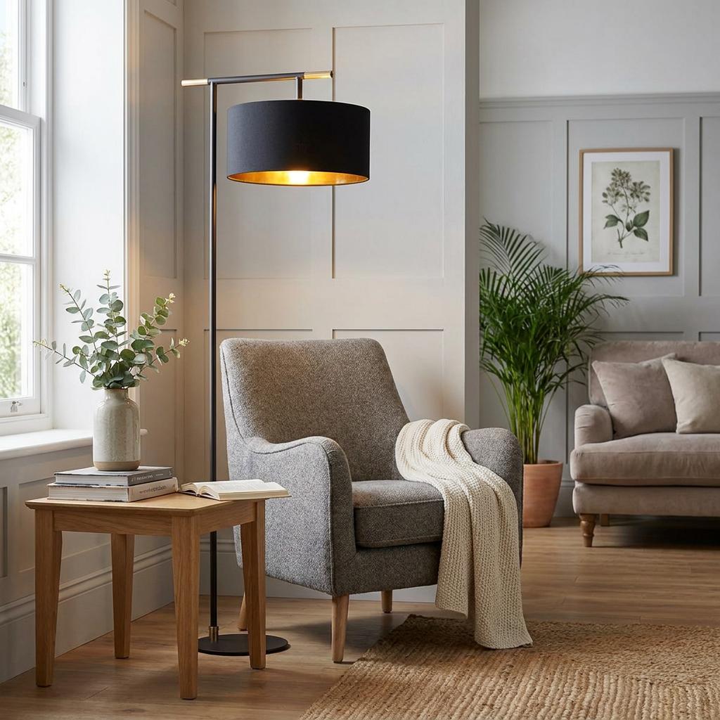 Balance Modern Brown & Brass Floor Lamp with a black drum shade over a grey armchair in a living room.