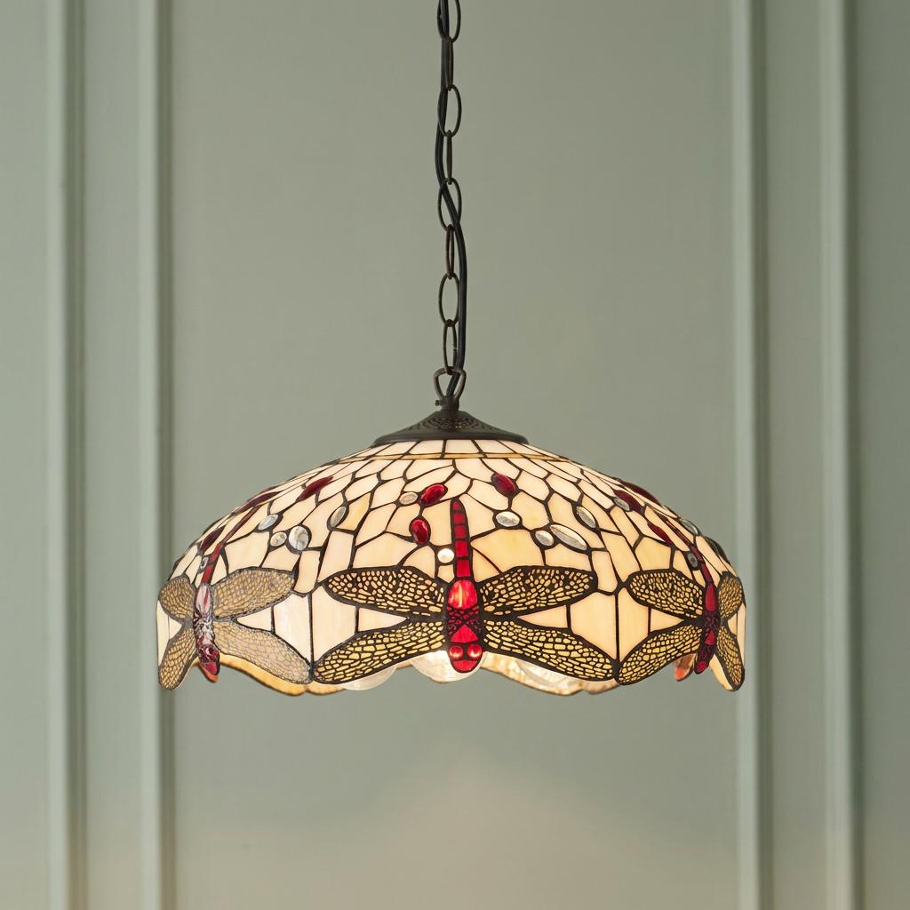 Beige dragonfly Tiffany ceiling pendant with red accents hangs from a chain against a light green paneled wall.