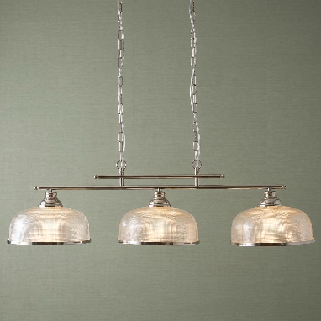Three-light silver bar pendant with textured holophane glass shades against a green textured wall background.