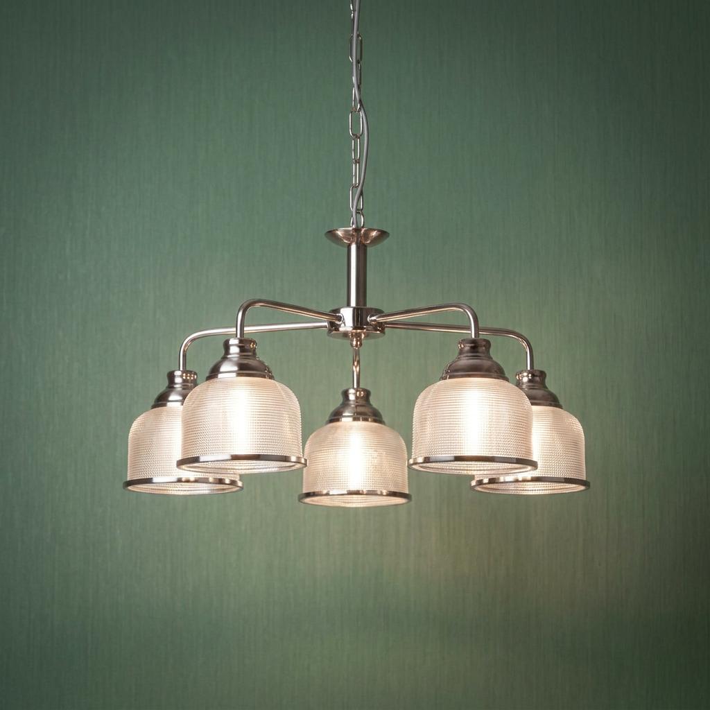 Silver five-light pendant with ribbed holophane glass shades against a textured green background.