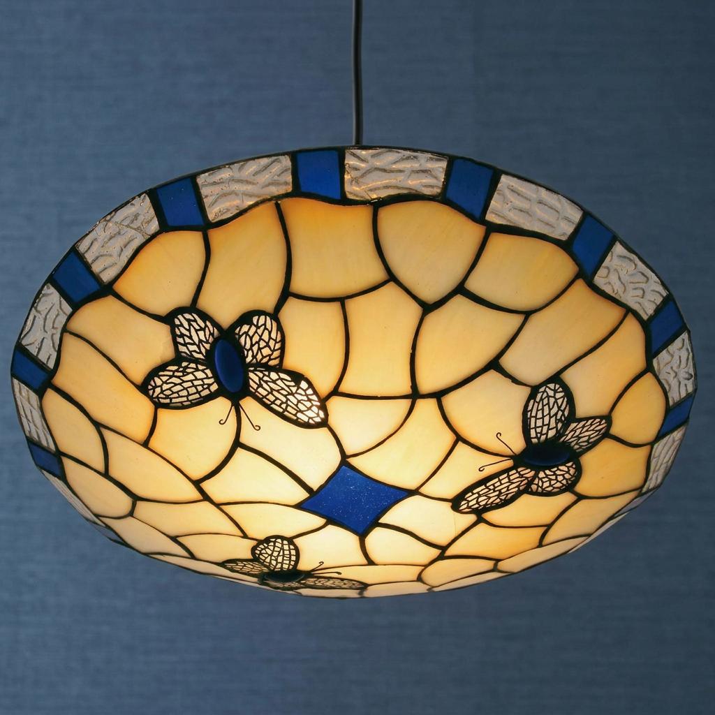 Round Tiffany ceiling lamp shade with blue butterfly motifs and cream stained glass, illuminated against a blue wall.