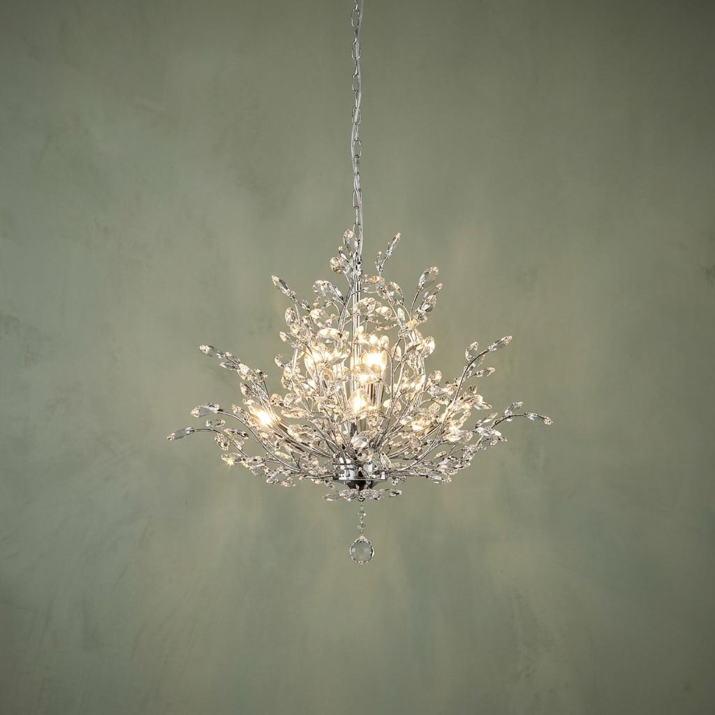 Bouquet 7-light chrome pendant with crystal glass branches glowing against a sage green wall.