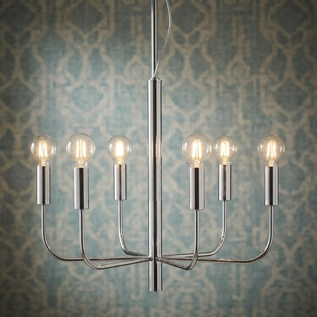 Brianna 6-light polished nickel chandelier with exposed bulbs in front of blue patterned wallpaper.