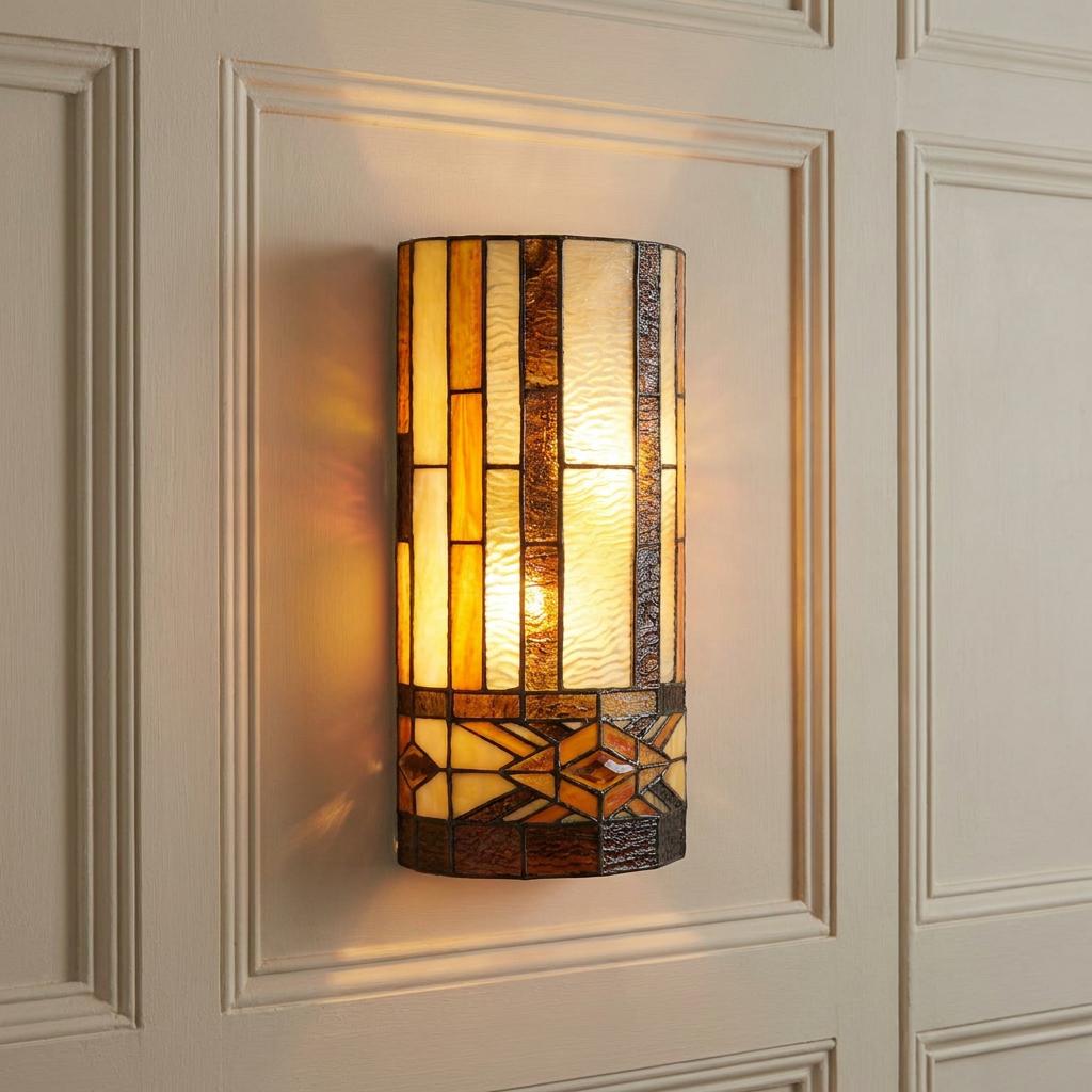 Illuminated Brunswick Tiffany wall light with amber and cream geometric panels on a cream paneled wall.