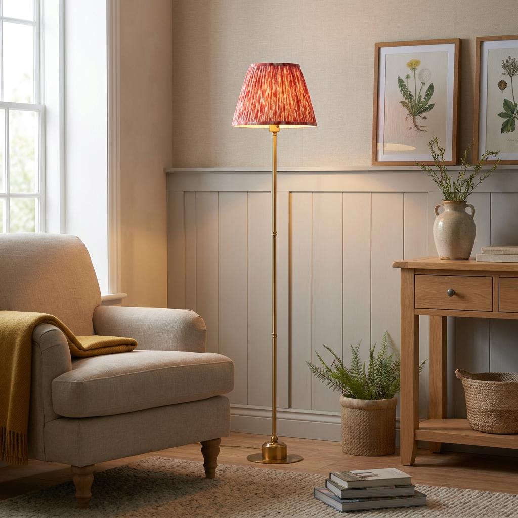 Burley brass floor lamp with a coral pink ikat shade in a cozy living room beside a beige armchair.