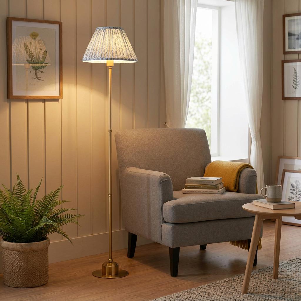 Brass floor lamp with a patterned blue shade illuminates a cozy living room corner with a grey armchair.