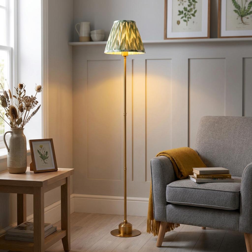 Slim brass floor lamp with a green zigzag shade in a cozy living room corner by a grey armchair.