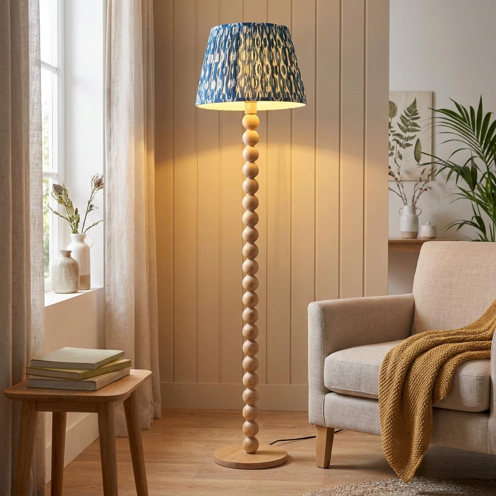 Beaded wooden floor lamp with a blue ikat pattern shade illuminating a cozy living room corner.