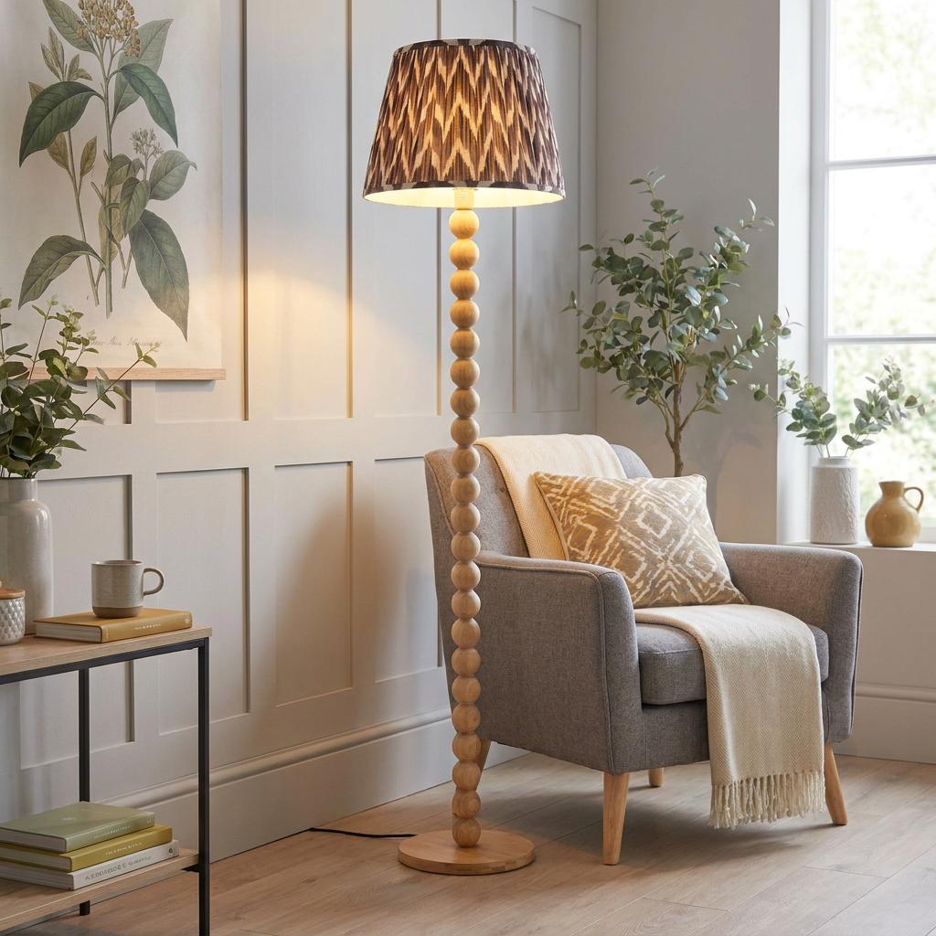 A Cane Bamboo floor lamp with a zigzag pearl grey shade standing beside a grey armchair in a cozy living room.