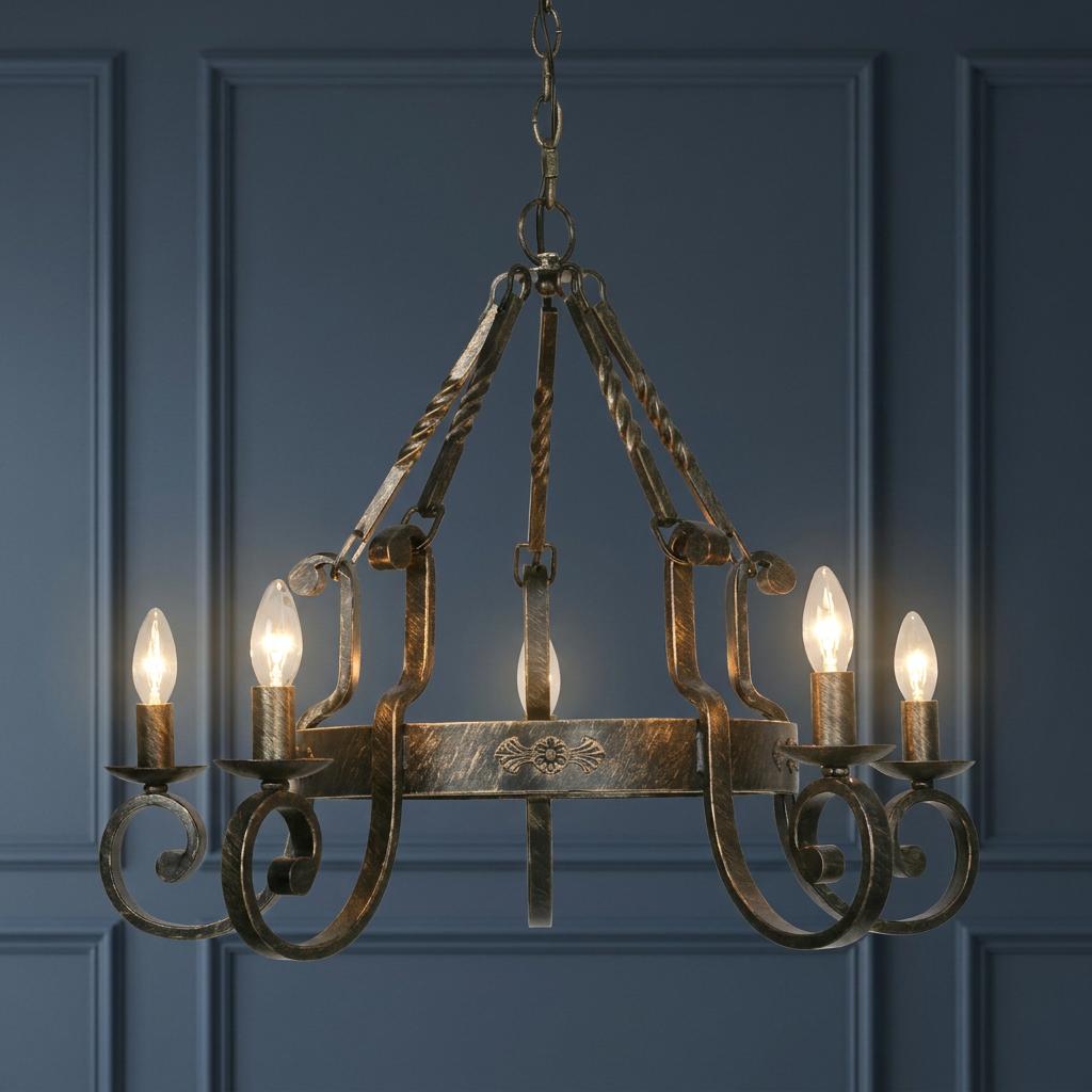 Traditional five-light chandelier in black and brushed gold finish with scroll details against a blue wall.