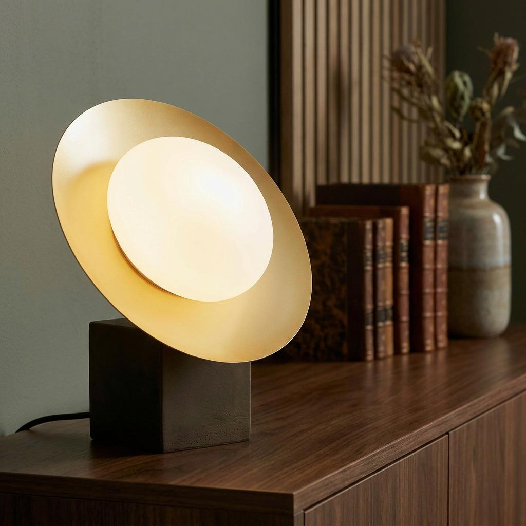 Modern table lamp with a gold disc reflector and opal glass shade on a dark bronze base.