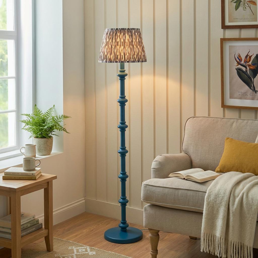 Carnaby blue spindle floor lamp with a grey ikat shade beside a neutral armchair in a cozy living room.