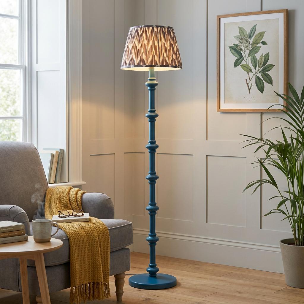 Blue turned wood floor lamp with a pearl grey zigzag shade in a cozy living room corner next to a grey armchair.