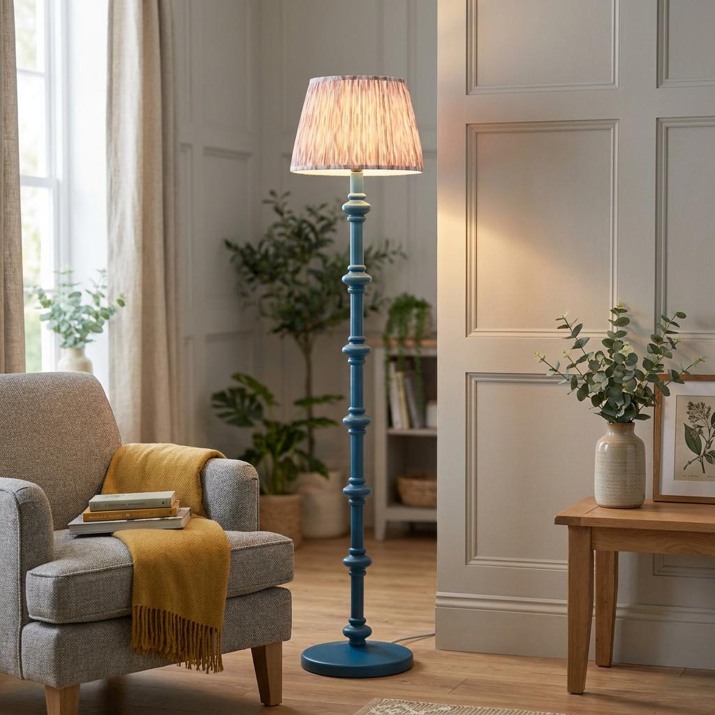Carnaby blue floor lamp with an ikat neutral shade standing in a cozy living room next to a gray armchair.