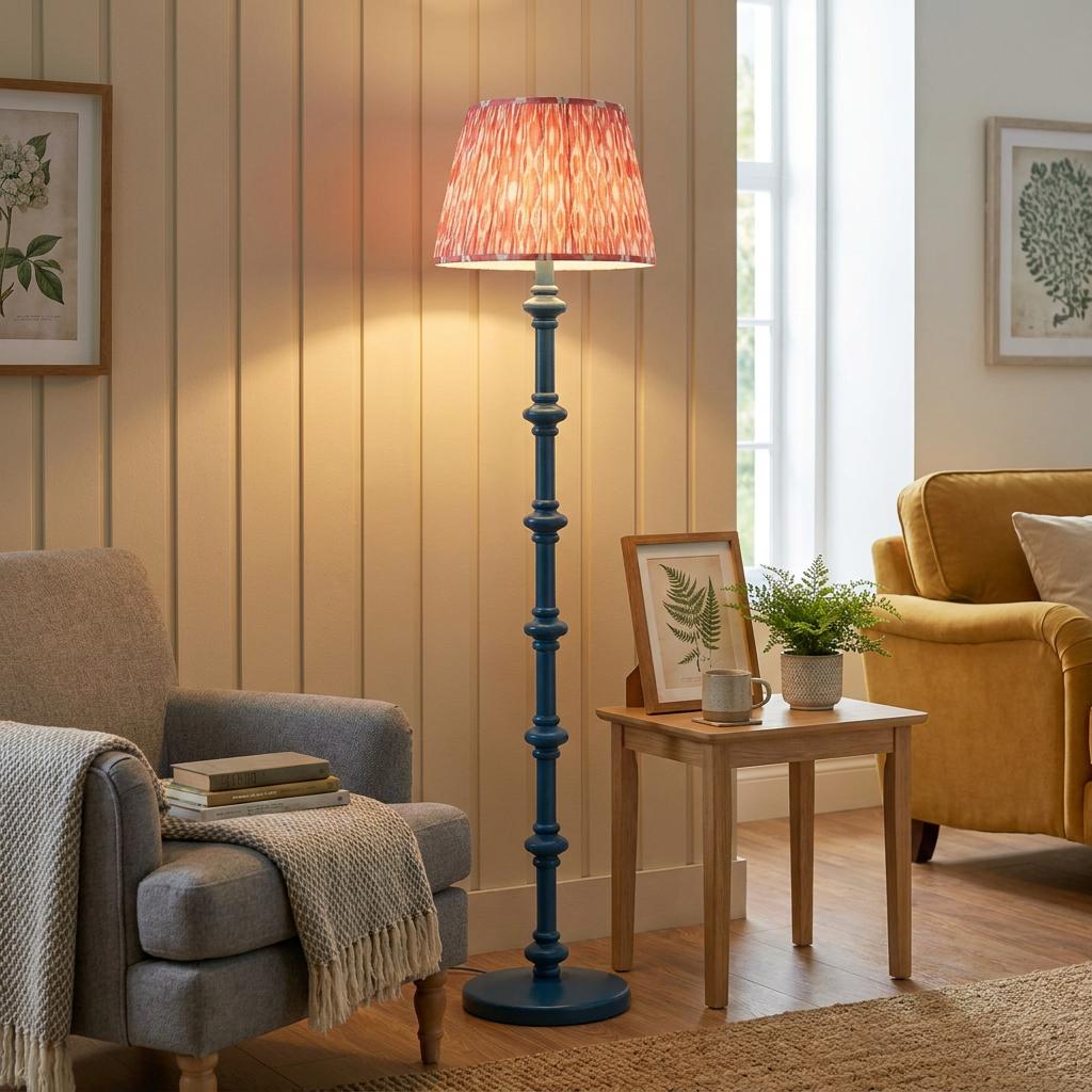 Blue bobbin floor lamp with a coral ikat shade illuminating a cozy living room with a grey armchair.