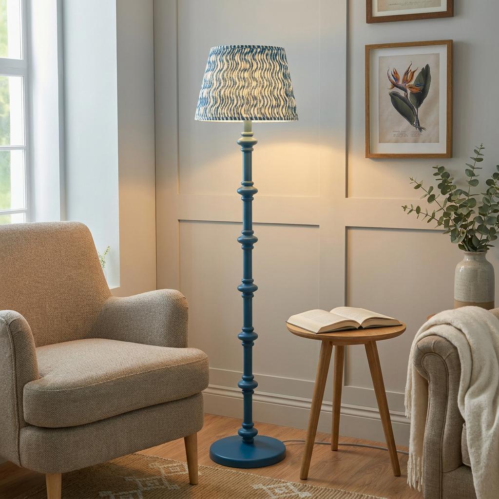 Blue spindle floor lamp with a wave-patterned shade in a cozy living room beside a beige armchair.