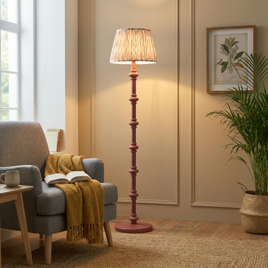 A pink bobbin floor lamp with a neutral ikat shade illuminates a cozy living room next to a grey armchair.