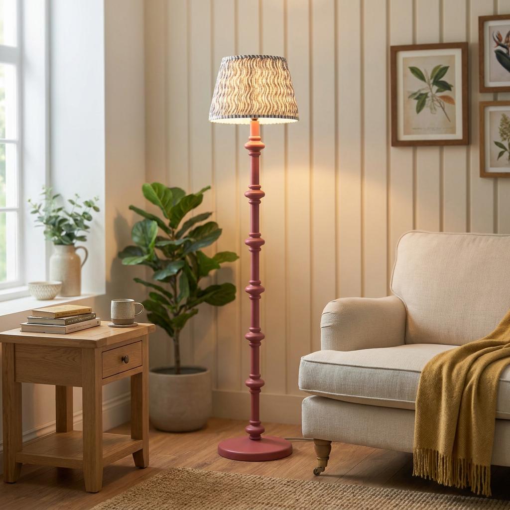 Pink bobbin-style floor lamp with a grey ripple shade stands in a cozy, neutral-toned living room.