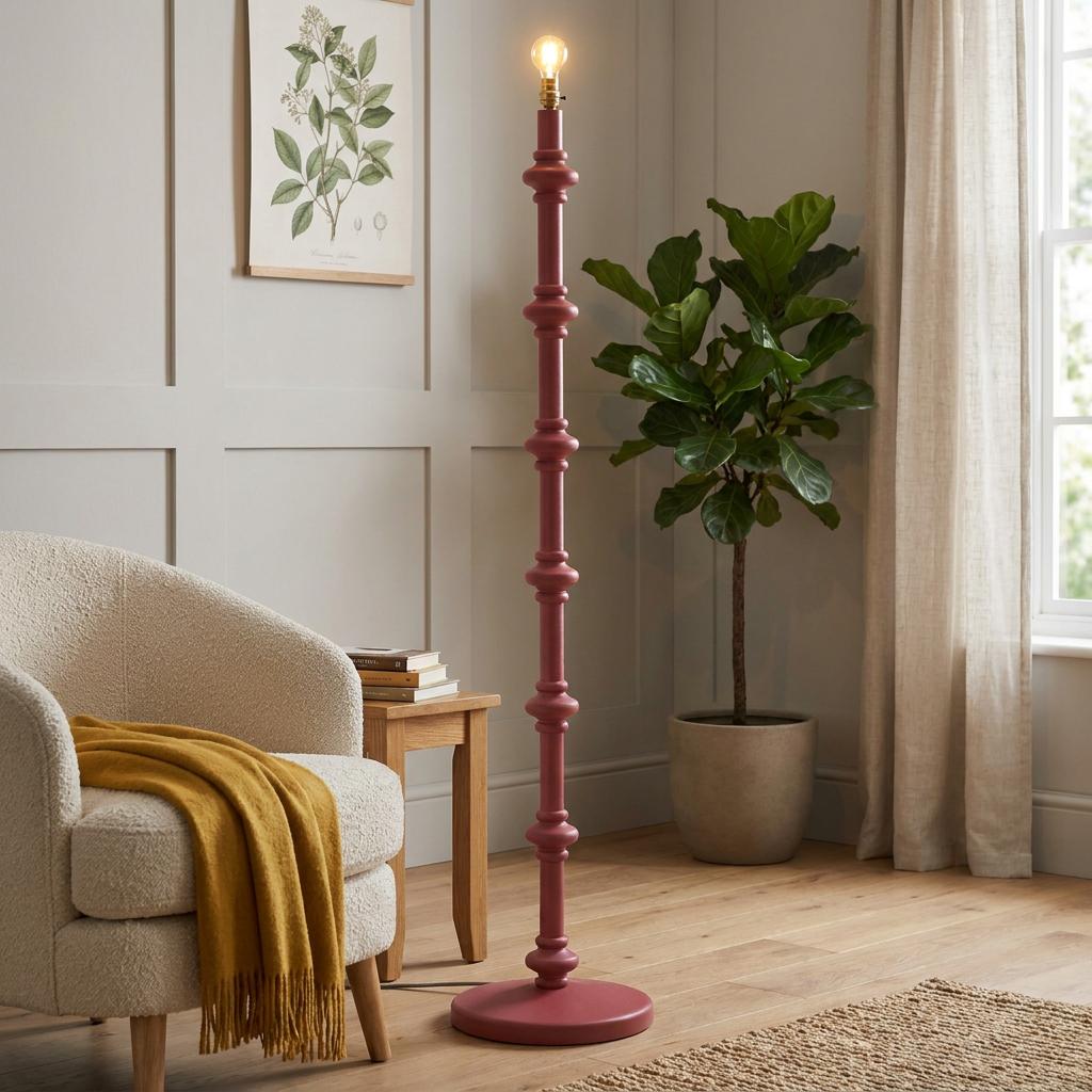 Tall, satin pink floor lamp base with decorative ridges in a cozy living room next to a white armchair.