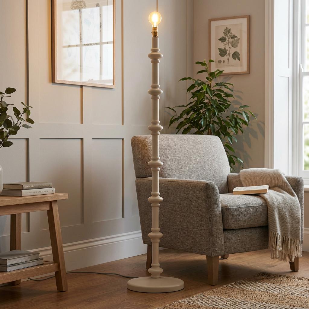Carnaby white wooden floor lamp base with a spindle design and exposed bulb next to a grey armchair in a living room.