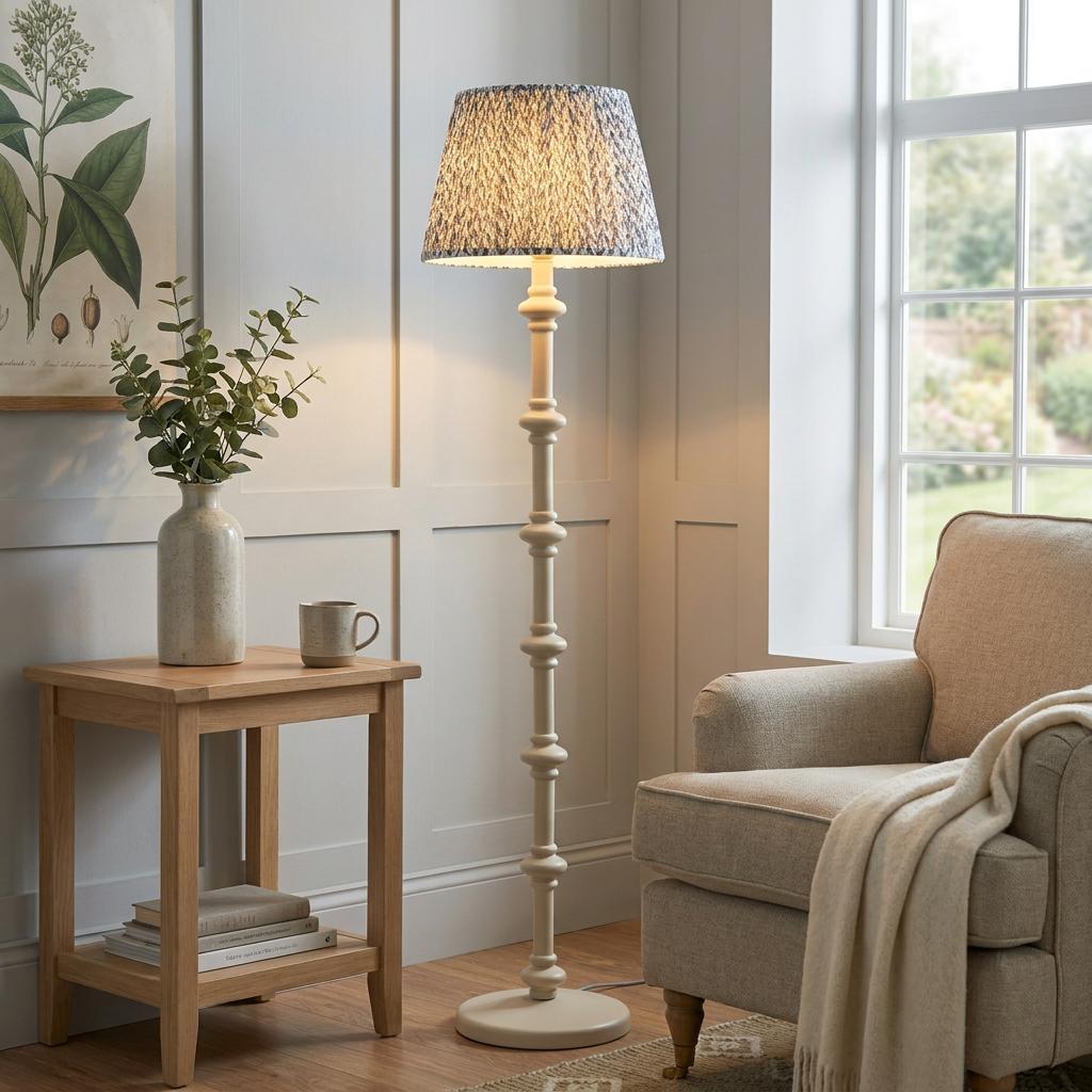 White turned wood floor lamp with a grey leaf pattern shade in a cozy living room corner next to an armchair.