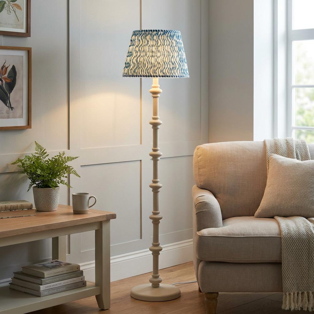 Carnaby white wooden floor lamp with a blue ripple pattern shade beside a neutral armchair in a cozy living room.