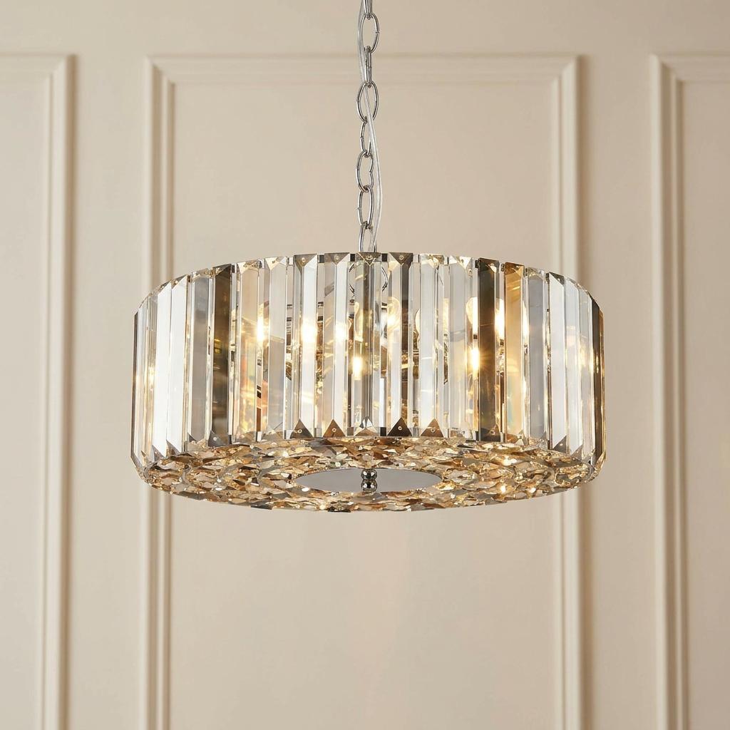 Chapeau chrome drum pendant with smoke and glass crystals glowing against a paneled wall.