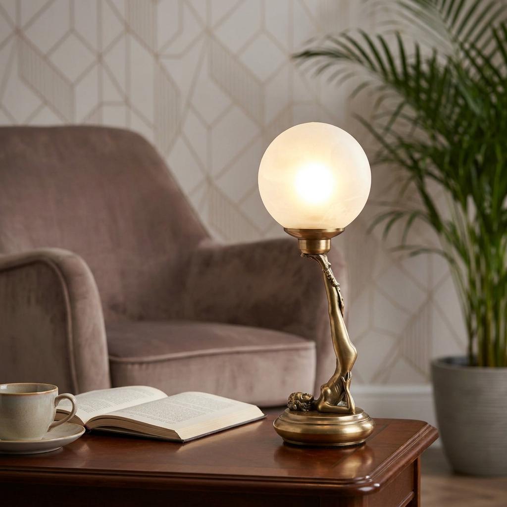 Art Deco brass figurine table lamp with a glowing frosted globe on a coffee table in a living room.