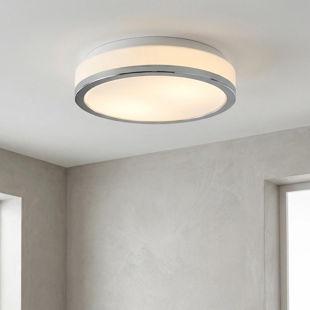 Circular flush mount bathroom ceiling light with a chrome rim and white glass shade on a plain ceiling.